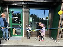 Barn klipper blågult band utanför byggnad.