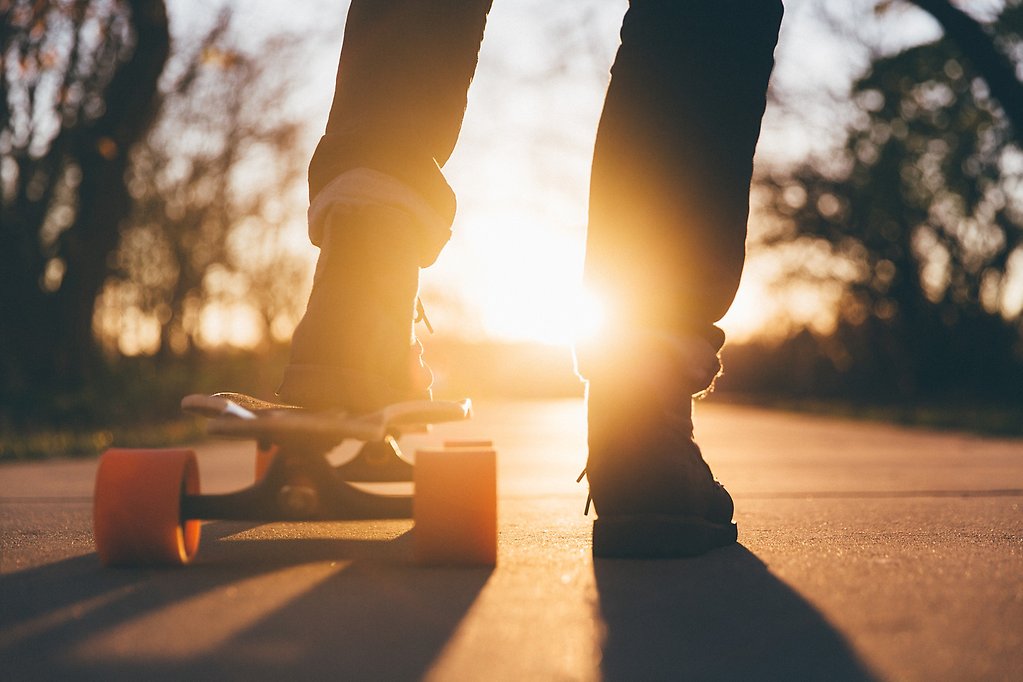 En fot på skateboard i solnedgång