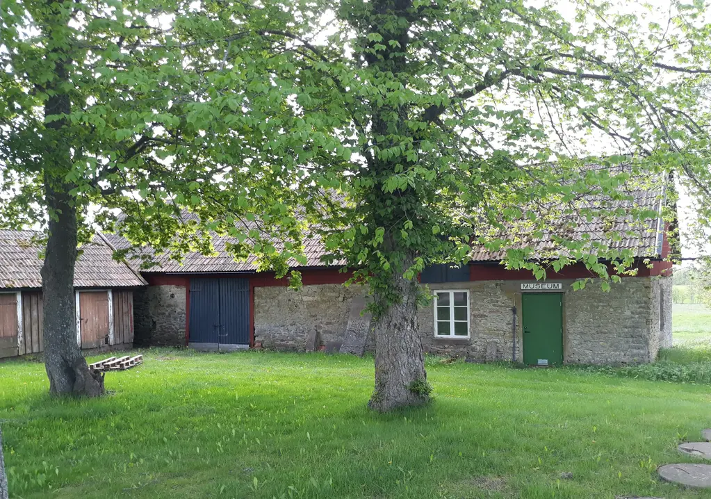 Visar foto av en gammal stenbyggnad med grönt gräs framför.
