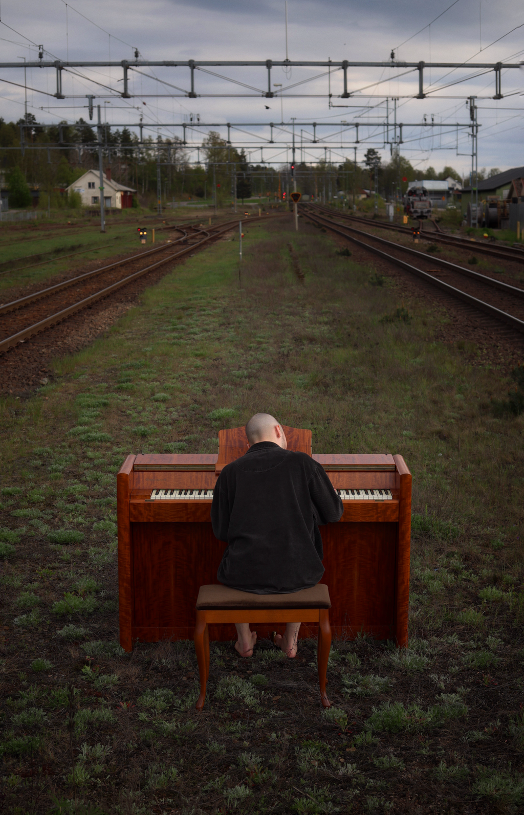 Man som sitter och spelar piano på en järnvägsräls.