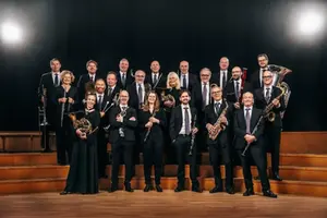 En grupp människor i mörka kläder står på en scen och håller i olika blåsinstrument.