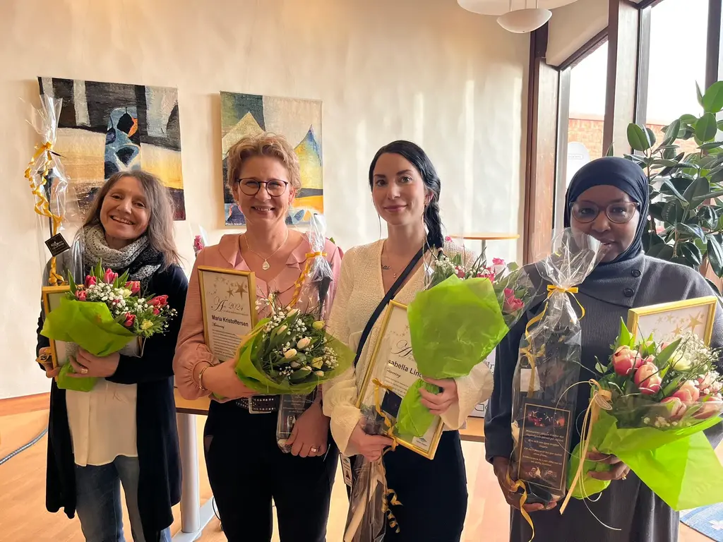 Fyra kvinnor står uppställda med blommor och diplom i händerna.