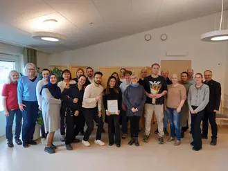Ett 20-tal personer står uppställda och ler mot kameran.