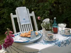 Bild på trädgårdsmöbler. Ett bord med kakfat och tekoppar i sommargrönskan.