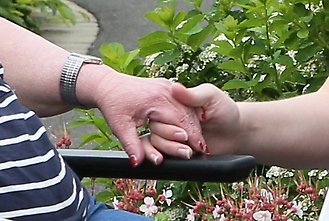 En kvinnas hand håller om en äldre kvinnas hand.