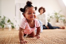 Bild på ett litet barn som kryper från en vuxen.