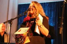 En kvinna som håller i ett pris och pratar i en mikrofon.