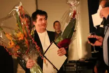 En man som håller i en blombukett och ett pris.