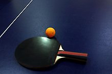 Ett blått bord, på bordet ligger ett svart rack med en liten orange boll vid sidan