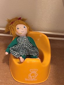 Bild på en docka som sitter på pottan.