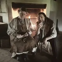 Två män sitter framför en brasa.