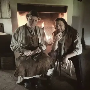 Två män sitter framför en brasa.