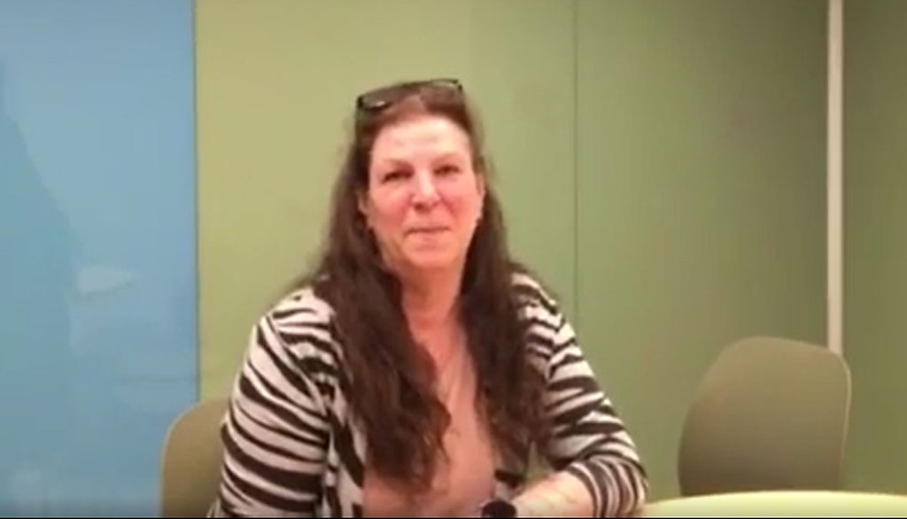 En kvinna som sitter vid ett bord och ler mot kameran.