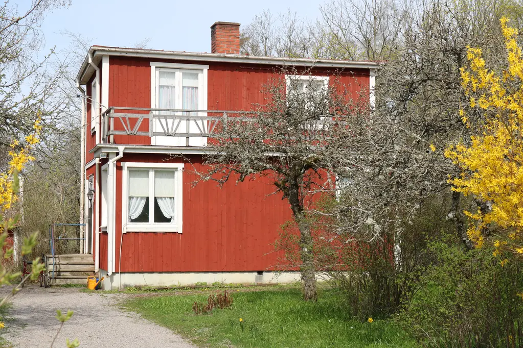 En bild som visar ett rödmålat bostadshus i två våningar.