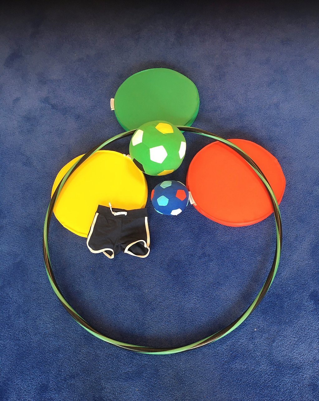 Bild på leksaker och idrottskläder på en blå matta.