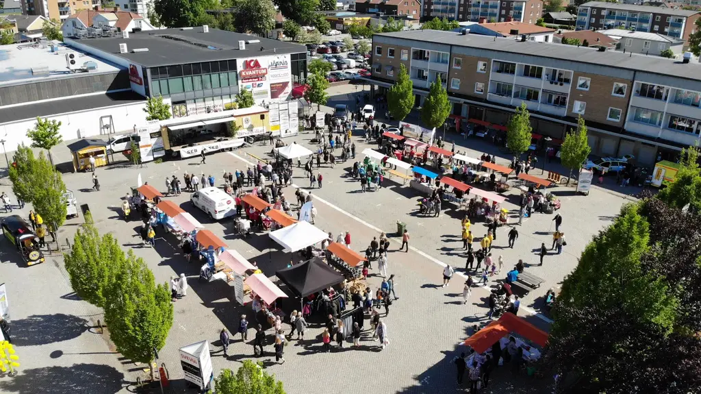 Drönarbild över stora torget i Götene, fyllt med marknadsstånd och besökare en solig Götenelördag 2019