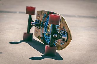 En skateboard liggandes på sidan med röda hjul och graffiti målning på undersidan.
