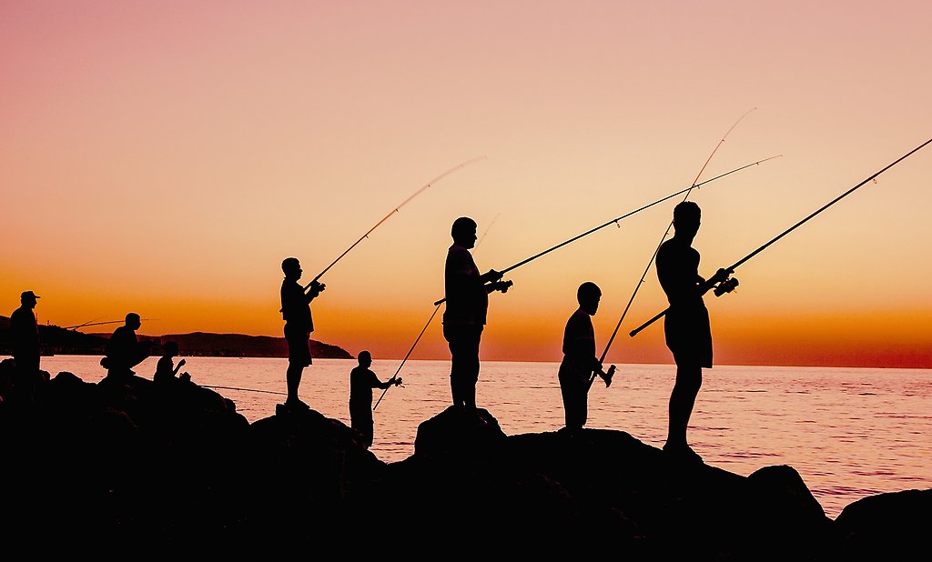 Några ungdomar fiskar från berget vid en solnedgång
