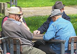 Äldre män sitter runt ett bord utomhus
