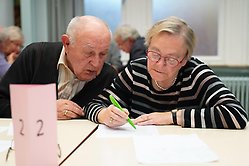 Äldre man och kvinna sitter vid ett bord inomhus