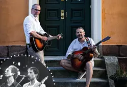 Två män framför en orange husfasad med varsin akustisk gitarr.