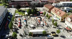 Drönarbild över stora torget i Götene, fyllt med marknadsstånd och besökare en solig Götenelördag.