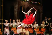 Kvinna i röd klänning gör ett baletthopp.