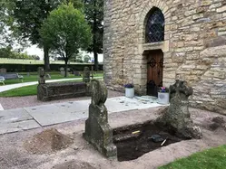 En gammal uppgräd grav utanför en kyrkport.