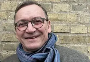 Man med glasögon som ler in i kameran.