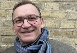 Man med glasögon som ler in i kameran.