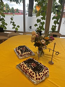 Bild på blåbär- och hallontårtor och vacker sommarbukett framför fönster med gurkgardiner.