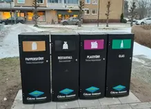 Fyra nya källsorteringskärl som står uppställda i en park i centrala Götene.